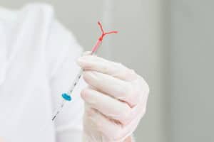 Médica com luvas cirúrgicas segura nas mãos um dispositivo anticoncepcional hormonal intra uterino (Diu)