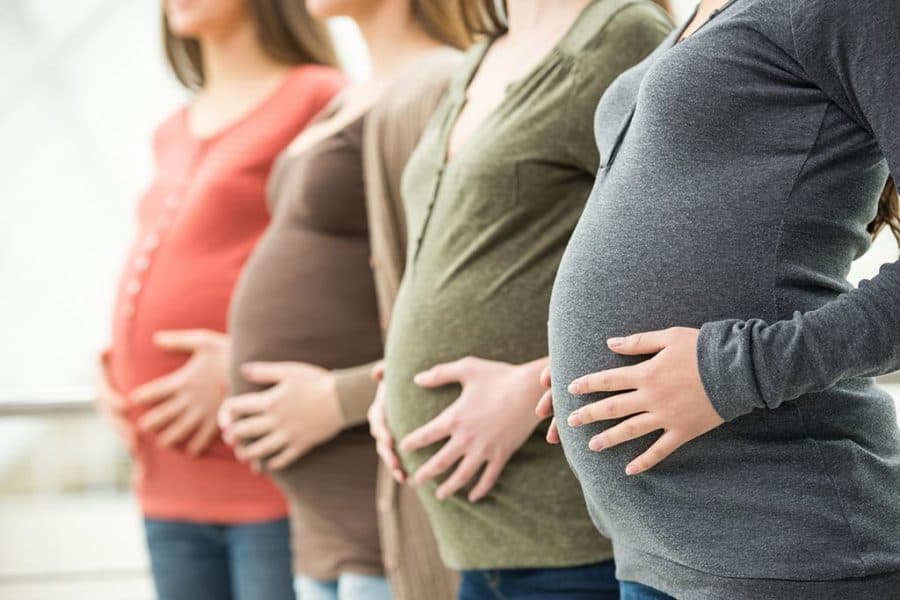 Diversas grávidas enfileiradas, cada uma de uma idade
