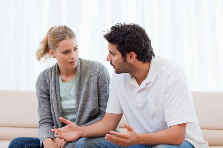 Casal sentado na sala com expressão tensa conversam sobre infertilidade masculina