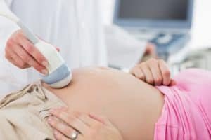 Dra. Luma faz exame de ultrassom na barriga de uma mulher grávida, no consultório